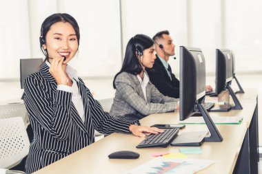Ofiste çalışan kulaklık takan işadamları uzak müşteri ya da meslektaşlarını desteklemek için çalışıyorlar. Arama merkezi, tele pazarlama, müşteri destek acentesi telefon görüşmesinde hizmet sunar.
