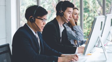 Ofiste çalışan kulaklık takan işadamları uzak müşteri ya da meslektaşlarını desteklemek için çalışıyorlar. Arama merkezi, tele pazarlama, müşteri destek acentesi telefon görüşmesinde hizmet sunar.