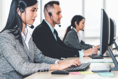Ofiste çalışan kulaklık takan işadamları uzak müşteri ya da meslektaşlarını desteklemek için çalışıyorlar. Arama merkezi, tele pazarlama, müşteri destek acentesi telefon görüşmesinde hizmet sunar.