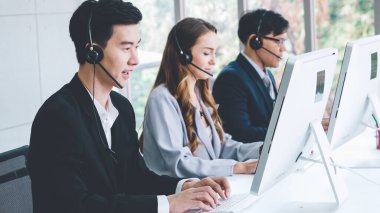 Ofiste çalışan kulaklık takan işadamları uzak müşteri ya da meslektaşlarını desteklemek için çalışıyorlar. Arama merkezi, tele pazarlama, müşteri destek acentesi telefon görüşmesinde hizmet sunar.