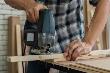 Marangoz atölyede ahşap işçiliği yapıyor. İnşaat malzemesi ya da ahşap mobilya üretiyor. Genç Asyalı marangoz zanaat için profesyonel araçlar kullanır. DIY üreticisi ve marangozluk konsepti.