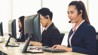 Ofiste çalışan kulaklık takan işadamları uzak müşteri ya da meslektaşlarını desteklemek için çalışıyorlar. Arama merkezi, tele pazarlama, müşteri destek acentesi telefon görüşmesinde hizmet sunar.