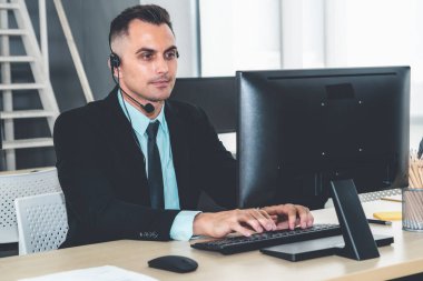 Ofiste çalışan kulaklık takan işadamları uzak müşteri ya da meslektaşlarını desteklemek için çalışıyorlar. Arama merkezi, tele pazarlama, müşteri destek acentesi telefon görüşmesinde hizmet sunar.