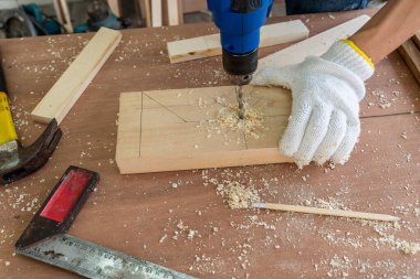 Marangoz atölyede ahşap işçiliği yapıyor. İnşaat malzemesi ya da ahşap mobilya üretiyor. Genç Asyalı marangoz zanaat için profesyonel araçlar kullanır. DIY üreticisi ve marangozluk konsepti.