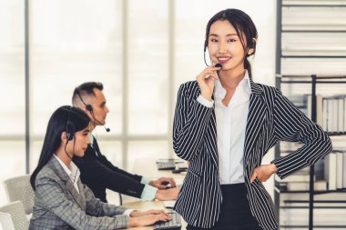 Ofiste çalışan kulaklık takan işadamları uzak müşteri ya da meslektaşlarını desteklemek için çalışıyorlar. Arama merkezi, tele pazarlama, müşteri destek acentesi telefon görüşmesinde hizmet sunar.