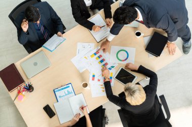 İş adamları grup toplantısı ofiste yukarıdan çekildi. İş kadınları, iş adamları ve ofis çalışanları, proje planlama belgeleriyle takım konferansında toplantı masasında çalışıyorlar. .