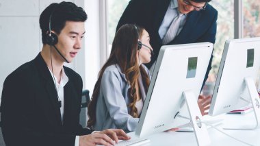 Ofiste çalışan kulaklık takan işadamları uzak müşteri ya da meslektaşlarını desteklemek için çalışıyorlar. Arama merkezi, tele pazarlama, müşteri destek acentesi telefon görüşmesinde hizmet sunar.