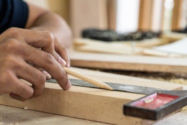 Marangoz atölyede ahşap işçiliği yapıyor. İnşaat malzemesi ya da ahşap mobilya üretiyor. Genç Asyalı marangoz zanaat için profesyonel araçlar kullanır. DIY üreticisi ve marangozluk konsepti.