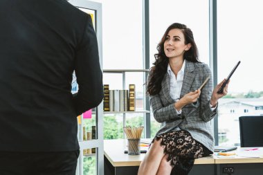 İki iş adamı toplantı odasında proje stratejisi hakkında konuşuyor. İş adamı, mali veri raporu hakkında sohbet ve tavsiyelerde bulunurken, modern işyerindeki iş arkadaşıyla proje planlamasını tartıştı.