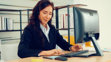 Ofiste çalışan kulaklık takan işadamları uzak müşteri ya da meslektaşlarını desteklemek için çalışıyorlar. Arama merkezi, tele pazarlama, müşteri destek acentesi telefon görüşmesinde hizmet sunar.