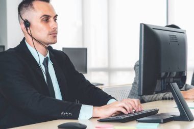 Ofiste çalışan kulaklık takan işadamları uzak müşteri ya da meslektaşlarını desteklemek için çalışıyorlar. Arama merkezi, tele pazarlama, müşteri destek acentesi telefon görüşmesinde hizmet sunar.