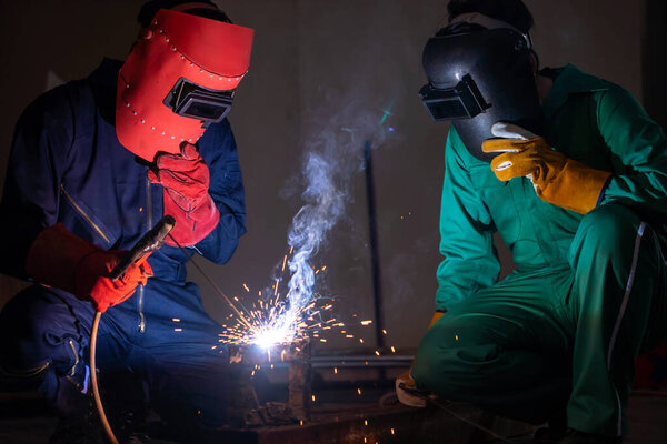 Metal welding steel works using electric arc welding machine to weld steel at factory. Metalwork manufacturing and construction maintenance service by manual skill labor concept.