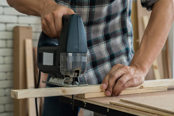 Плотник, работающий в мастерской по производству строительных материалов или деревянной мебели. Молодой азиатский плотник использует профессиональные инструменты для ремесла. DIY производитель и плотницкие работы концепция.