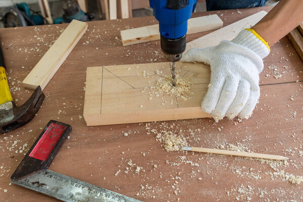 Carpenter working on wood craft at workshop to produce construction material or wooden furniture. The young Asian carpenter use professional tools for crafting. DIY maker and carpentry work concept.