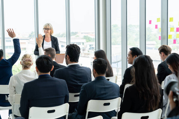 Group of business people meeting in a seminar conference . Audience listening to instructor in employee education training session . Office worker community summit forum with expert speaker .