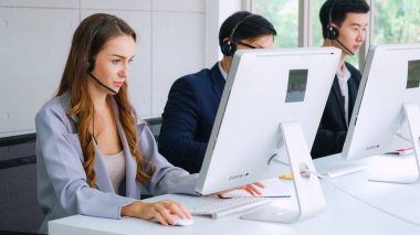 Ofiste çalışan kulaklık takan işadamları uzak müşteri ya da meslektaşlarını desteklemek için çalışıyorlar. Arama merkezi, tele pazarlama, müşteri destek acentesi telefon görüşmesinde hizmet sunar.