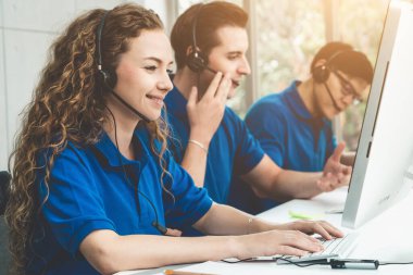 Ofiste çalışan kulaklık takan işadamları uzak müşteri ya da meslektaşlarını desteklemek için çalışıyorlar. Arama merkezi, tele pazarlama, müşteri destek acentesi telefon görüşmesinde hizmet sunar.