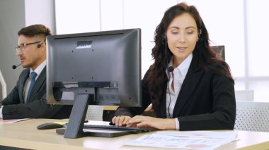 Ofiste çalışan kulaklık takan işadamları uzak müşteri ya da meslektaşlarını desteklemek için çalışıyorlar. Arama merkezi, tele pazarlama, müşteri destek acentesi telefon görüşmesinde hizmet sunar.