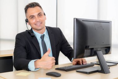 Ofiste çalışan kulaklık takan işadamları uzak müşteri ya da meslektaşlarını desteklemek için çalışıyorlar. Arama merkezi, tele pazarlama, müşteri destek acentesi telefon görüşmesinde hizmet sunar.