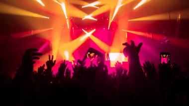 Happy people dance in nightclub DJ party concert and listen to electronic dancing music from DJ on the stage. Silhouette cheerful crowd celebrate New Year party 2020. People lifestyle DJ nightlife. clipart
