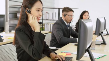 Ofiste çalışan kulaklık takan işadamları uzak müşteri ya da meslektaşlarını desteklemek için çalışıyorlar. Arama merkezi, tele pazarlama, müşteri destek acentesi telefon görüşmesinde hizmet sunar.
