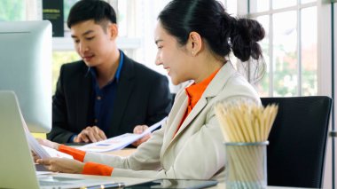 İki iş adamı toplantı odasında proje stratejisi hakkında konuşuyor. İş adamı, mali veri raporu hakkında sohbet ve tavsiyelerde bulunurken, modern işyerindeki iş arkadaşıyla proje planlamasını tartıştı.