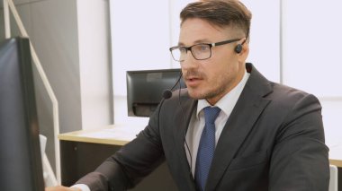 Ofiste çalışan kulaklık takan işadamları uzak müşteri ya da meslektaşlarını desteklemek için çalışıyorlar. Arama merkezi, tele pazarlama, müşteri destek acentesi telefon görüşmesinde hizmet sunar.