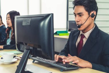 Ofiste çalışan kulaklık takan işadamları uzak müşteri ya da meslektaşlarını desteklemek için çalışıyorlar. Arama merkezi, tele pazarlama, müşteri destek acentesi telefon görüşmesinde hizmet sunar.