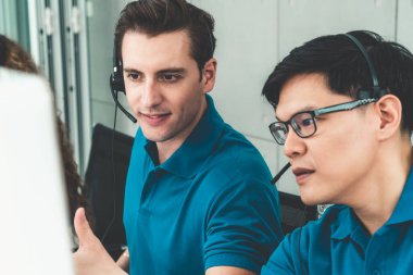 Ofiste çalışan kulaklık takan işadamları uzak müşteri ya da meslektaşlarını desteklemek için çalışıyorlar. Arama merkezi, tele pazarlama, müşteri destek acentesi telefon görüşmesinde hizmet sunar.