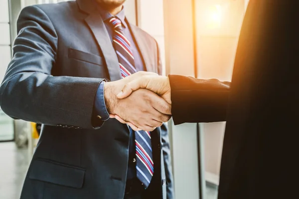 Business people handshake in corporate office showing professional agreement on a financial deal contract.