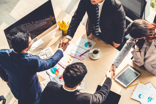 Group business people handshake at meeting table in office together with confident shot from top view . Young businessman and businesswoman workers express agreement of investment deal.