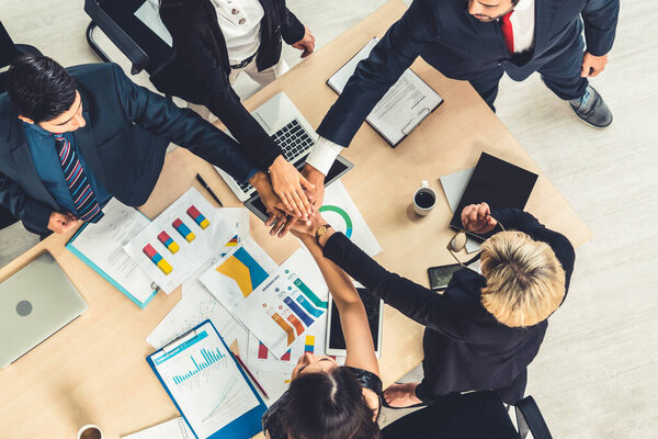 Happy business people celebrate teamwork success together with joy at office table shot from top view . Young businessman and businesswoman workers express cheerful victory showing unity and support .