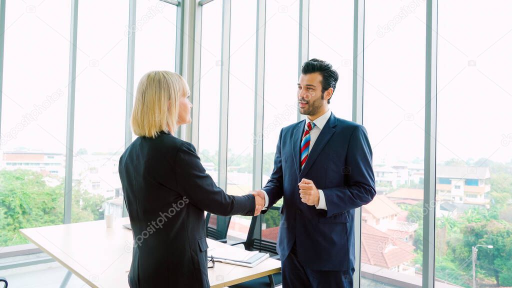 Business people handshake in corporate office showing professional agreement on a financial deal contract.