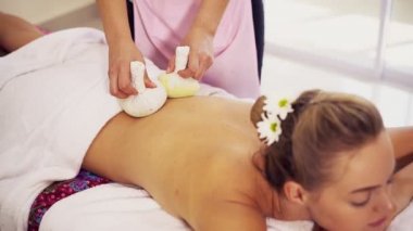 Kadın üzerinde bitkisel baskı uygulayan masaj terapisti..