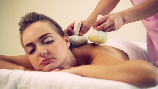 Masaż terapeuta przy użyciu kompresu ziołowego na kobiecie. — Wideo stockowe