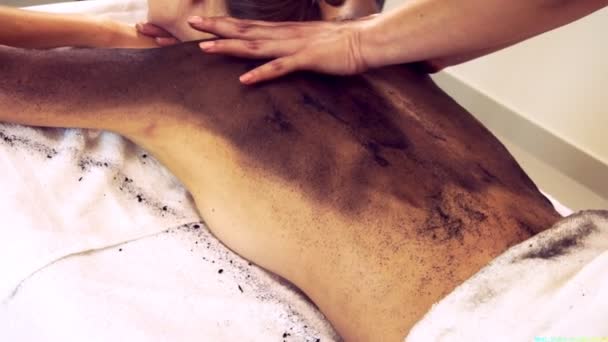 Ontspannen vrouw liggend op spa bed voor lichaam schrobben massage met behulp van traditionele kruid — Stockvideo