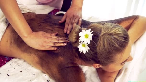 Ontspannen vrouw liggend op spa bed voor lichaam schrobben massage met behulp van traditionele kruid — Stockvideo