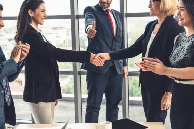 Şirket ofisinde iş adamları el sıkışır.