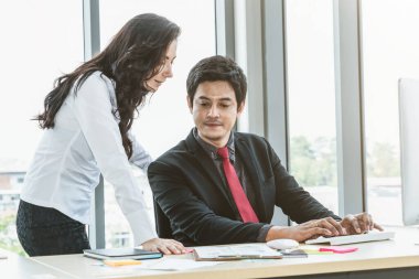 İki iş adamı toplantı odasında proje stratejisi hakkında konuşuyor. İş adamı, mali veri raporu hakkında sohbet ve tavsiyelerde bulunurken, modern işyerindeki iş arkadaşıyla proje planlamasını tartıştı.