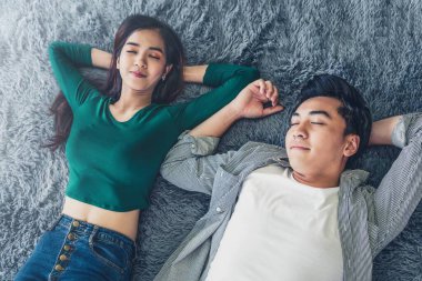 Mutlu Asyalı çift oturma odasının zemininde birlikte yatıyorlar. Aşk ilişkisi ve yaşam tarzı kavramı.