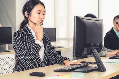 Ofiste çalışan kulaklık takan işadamları uzak müşteri ya da meslektaşlarını desteklemek için çalışıyorlar. Arama merkezi, tele pazarlama, müşteri destek acentesi telefon görüşmesinde hizmet sunar.