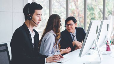 Ofiste çalışan kulaklık takan işadamları uzak müşteri ya da meslektaşlarını desteklemek için çalışıyorlar. Arama merkezi, tele pazarlama, müşteri destek acentesi telefon görüşmesinde hizmet sunar.