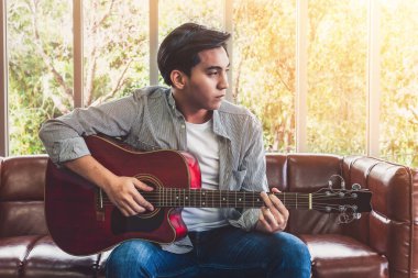 Genç gitarist gitarını evde tutuyor. Müzik ve şarkı konsepti.