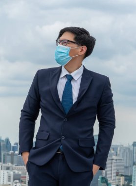 Coronavirus veya COVID-19 yüzünden yüz maskesi olan genç bir ofis çalışanı. Coronavirus veya COVID-19 'un yayılmasını engellemek ve işletmeyi yeniden açmak için koruyucu çalışma ortamı kavramı.