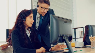 Ofiste çalışan kulaklık takan işadamları uzak müşteri ya da meslektaşlarını desteklemek için çalışıyorlar. Arama merkezi, tele pazarlama, müşteri destek acentesi telefon görüşmesinde hizmet sunar.