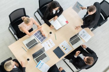 İş adamları grup toplantısı ofiste yukarıdan çekildi. İş kadınları, iş adamları ve ofis çalışanları, proje planlama belgeleriyle takım konferansında toplantı masasında çalışıyorlar. .