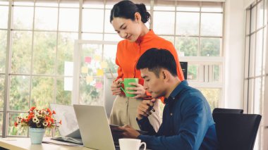 İki iş adamı toplantı odasında proje stratejisi hakkında konuşuyor. İş adamı, mali veri raporu hakkında sohbet ve tavsiyelerde bulunurken, modern işyerindeki iş arkadaşıyla proje planlamasını tartıştı.