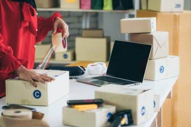 Çevrimiçi satıcı ev ofisinde çalışıyor ve teslimat kutusunu müşteriye paketliyor. İnternette e-ticaret yapan küçük işletme sahibi ya da girişimci.