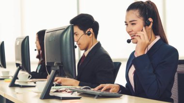 Ofiste çalışan kulaklık takan işadamları uzak müşteri ya da meslektaşlarını desteklemek için çalışıyorlar. Arama merkezi, tele pazarlama, müşteri destek acentesi telefon görüşmesinde hizmet sunar.