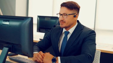 Ofiste çalışan kulaklık takan işadamları uzak müşteri ya da meslektaşlarını desteklemek için çalışıyorlar. Arama merkezi, tele pazarlama, müşteri destek acentesi telefon görüşmesinde hizmet sunar.